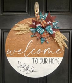 a welcome to our home sign hanging on the front door with fall leaves and ribbons