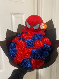 a person holding a bouquet of red, white and blue flowers in front of a door