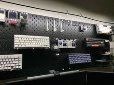 there are many keyboards and mouses on the wall in this office area with black pegboard