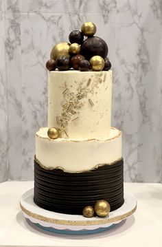 a three tiered cake with gold and black decorations