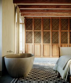 a bath tub sitting next to a bed in a room with wood paneled walls