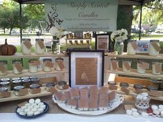 an outdoor display with candles and other items for sale on the table in front of it