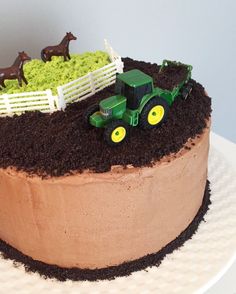 a cake with chocolate frosting and green icing on the top is decorated with farm animals