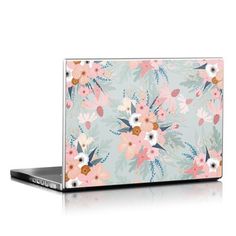 an open laptop computer sitting on top of a white surface with pink and blue flowers