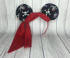 a mickey mouse ears headband with skull and crossbones on it, tied to a white wooden background