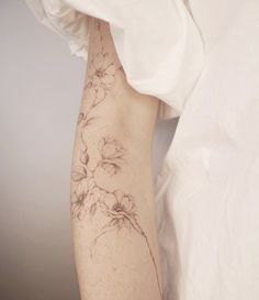 a woman's arm with flowers on it and a white shirt behind her,