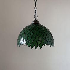 a green stained glass light hanging from a ceiling fixture in a room with white walls