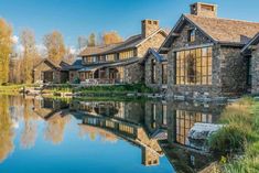 a large house sitting next to a body of water in the middle of a forest