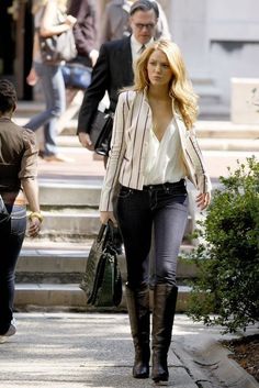 a woman is walking down the street with her hand in her pockets and holding a purse