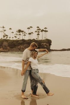 a man and woman hugging on the beach with palm trees in the backgroud