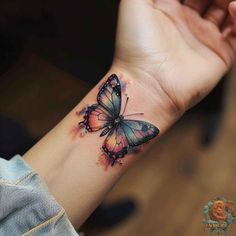 a woman's wrist with a watercolor butterfly tattoo on the left side of her arm