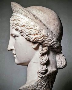 a statue of a woman's head with braids on her hair, wearing a hat