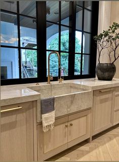 a kitchen with marble counter tops and wooden cabinets, along with a large window that looks out onto the outdoors