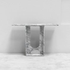 a white marble table with a square shaped object on it's side in front of a wall