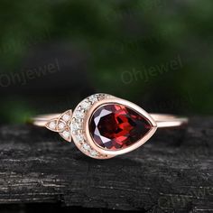 a close up view of a ring with a red stone and white diamonds on it