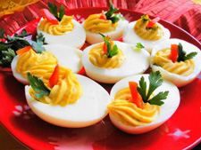 deviled eggs with mustard and parsley on a red plate, ready to be eaten