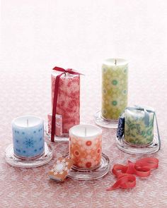 four candles are sitting on a table next to each other with bows and ribbons around them