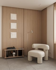 a white chair sitting in front of a wooden wall next to a table with a record player on it