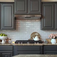 a kitchen with gray cabinets and marble counter tops