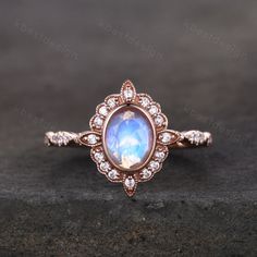 a ring with an oval shaped blue stone surrounded by small white diamonds on a black surface