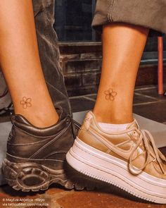 two people standing next to each other with small tattoos on their legs and feet,