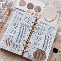 an open planner with pink and gold accents on top of a white carpeted floor