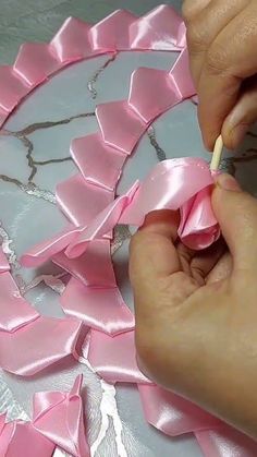 someone is decorating a cake with pink ribbon