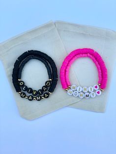 two black and pink bracelets sitting next to each other on top of a white bag