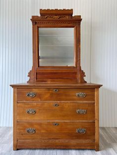 a wooden dresser with a mirror on top of it and drawers in front of it