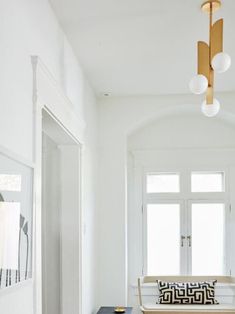 a white hallway with black and white pillows on the floor, an area rug in between two windows