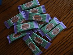 candy bar wrappers with footballs on them sitting on a wooden table next to a cupcake