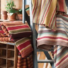 multicolored striped towels stacked on top of each other in front of a shelf