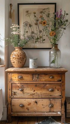 an old dresser with flowers in vases on top