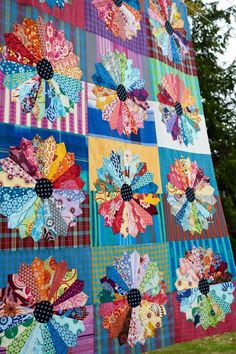 a colorful quilt hanging from the side of a tree