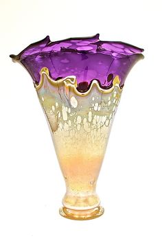 a purple glass vase sitting on top of a white table