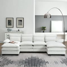 a large white sectional sofa sitting in a living room next to a tall floor lamp