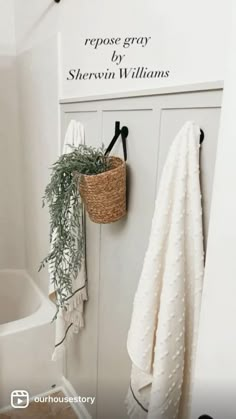 a white bathroom with towels hanging on the wall and a towel rack in the corner