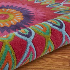 the colorful rug is laying on the wooden floor