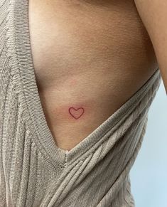 a woman's stomach with a small heart tattoo on her left side ribcage