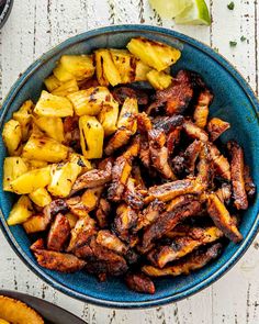 a blue bowl filled with meat and pineapples