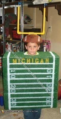 a young boy dressed as a football player in front of a green box with numbers on it