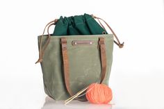 a green bag with a ball of yarn next to it