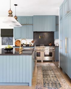 a kitchen with blue cabinets and an area rug in front of the stove top oven