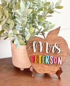 an apple shaped wooden sign with the word mr and mrs on it next to a potted plant