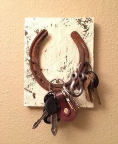 a bunch of keys hanging from a hook on the side of a wall with a horse shoe