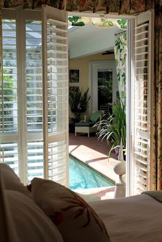 an open door leading to a bedroom with a pool in the middle and lots of windows