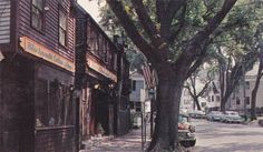 an old fashioned street with cars parked on the side