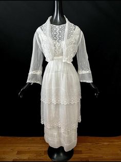 Beautiful antique Edwardian fine white cotton organdy tired dress. Lovely light sheer organdy fabric with delicate floral embroidered details throughout. The dress has a shawl style collar with lapels to the waist. It has two tiers of organdy, the bottom portion of the dress is made of fine lawn cotton. It has long sleeves that feature split bell cuffs trimmed with Valenciennes lace, the sleeves also have a especially pretty lace details above the cuffs. The dress snaps closed on the side hip an Delicate White Dress For Daywear, White Victorian Wedding Dress For Summer, Vintage White Victorian Dress With Broderie Anglaise, White Broderie Anglaise Regency Dress, White Regency Broderie Anglaise Dresses, White Elegant Victorian Dress With Broderie Anglaise, Vintage Broderie Anglaise Wedding Dress, White Regency Style Broderie Anglaise Dresses, White Victorian Dress With Lace Trim For Garden Party