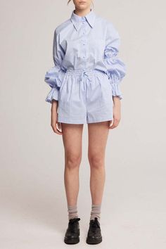 Made-to-order - please allow 2-3 weeks for this product to ship. learn more.    size guide    the oversized poplin gathered sleeve shirt in baby blue pinstripes. this cotton shirt is a relaxed fit with drop shoulders and dreamy full gathered sleeves. featuring fabric covered buttons a front pocket and a pointy structured collar. designed to be worn with the matching shorts or skirt.    the facts:    ✄ locally made            🍃 natural fibre    🐇 soft feel                  ☁️ loose and comfy    product details    - made in australia  - soft cotton poplin fabric    - oversized fit drop shoulder  - self covered buttons  - gathered elastic sleeves  - extended pointy collar  - model is 178cm / 5'10" and wears a size 1    fabric & care    95% cotton / 5% elastane    medium-light weight shirtin Casual Blue Poplin Shirt, Oversized Button-up Top With Placket, Light Blue Oversized Top With Button Closure, Relaxed Fit Poplin Button-up Top, Oversized Poplin Button-up Top, Oversized Poplin Shirt, Collar Model, Pointy Collar, Elastic Sleeves