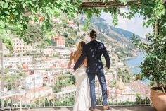 a bride and groom are looking out over the amalfa village from their balcony